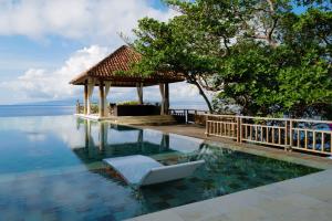 a swimming pool with a chair in the water at Raaga Samudra Villa in Padangbai