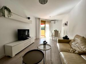 ein Wohnzimmer mit einem Sofa, einem TV und einem Tisch in der Unterkunft Apartamento con encanto en playa in Fuengirola