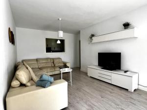 ein Wohnzimmer mit einem Sofa und einem Flachbild-TV in der Unterkunft Apartamento con encanto en playa in Fuengirola