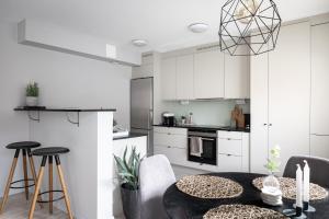 a kitchen with white cabinets and a black table and chairs at Peaceful Scandinavian Studio - 19mins from City Centre in Stockholm