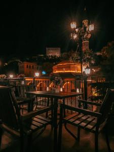 einen Tisch und Stühle auf einer Terrasse in der Nacht in der Unterkunft Alsara Guesthouse in Gjirokastër