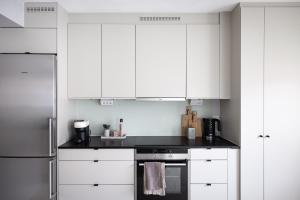 a kitchen with white cabinets and a stove top oven at Peaceful Scandinavian Studio - 19mins from City Centre in Stockholm