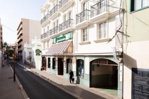 a person walking down a street next to a building at Rooms & Suites Loft 2G Deluxe Edition Arrecife in Arrecife