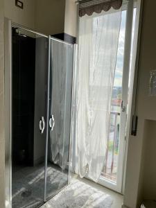 baño con ducha con puerta de cristal y ventana en Casa Aurora, en Segrate