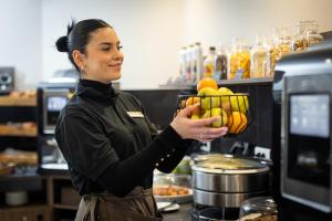 a woman holding a bowl of fruit in a kitchen at Hotel Khla Nice in Nice