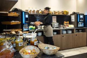 a woman standing in a kitchen preparing food at Hotel Khla Nice in Nice