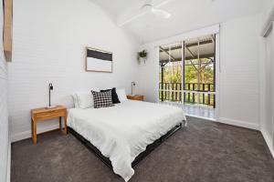 a white bedroom with a bed and a window at Bellbird Lodge Barrington Tops in Bandon Grove