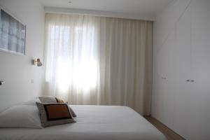 a white bedroom with a bed and a window at La petite chaumine in Saint-Nazaire