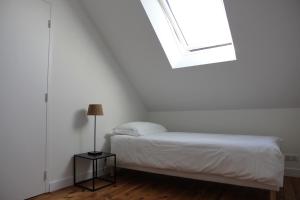 a white bedroom with a bed and a window at La petite chaumine in Saint-Nazaire