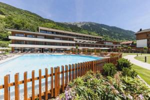 un complexe avec une grande piscine en face d'un bâtiment dans l'établissement Alpenhotel Montafon, à Schruns