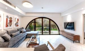 a living room with a couch and a tv at Holysuite David's Village in Jerusalem