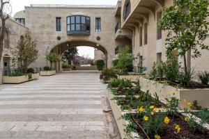 een toegang tot een gebouw met een binnenplaats met bloemen bij Holysuite David's Village in Jeruzalem
