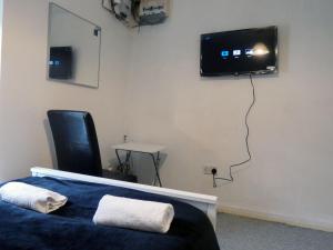 um quarto com uma cama e uma televisão na parede em Bridge Street En Suite Rooms em Merthyr Tydfil