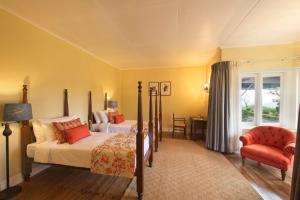 a bedroom with two beds and a chair and a window at Ama Stays and Trails Tea Estate Bungalows , Munnar in Munnar