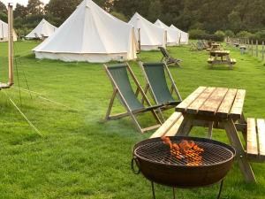 a grill and a picnic table and some tents at Home Farm Radnage Glamping Bell Tent 8, with Log Burner and Fire Pit in High Wycombe