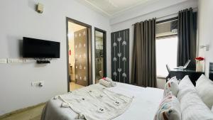 a bedroom with a white bed and a television at BluO 1BHK Medanta Medicity, Kitchen, Balcony, Lift in Gurgaon