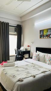 a large white bed in a room with a desk at BluO 1BHK Medanta Medicity, Kitchen, Balcony, Lift in Gurgaon
