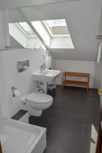 a bathroom with a toilet and a sink and a skylight at Abendruhe Hotel - kontaktloser Check In in Oberhaching