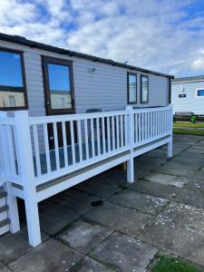 a mobile home with a white railing on a patio at Oscars caravan in Abergele