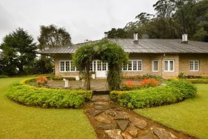 a house with a garden in front of it at Ama Stays and Trails Tea Estate Bungalows , Munnar in Munnar