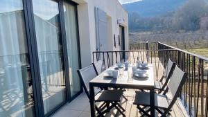 una mesa y sillas en un balcón con vistas en Les Papillons du Ventoux - La Petite Tortue - één slaapkamer met terras en Malaucène