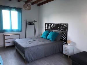 Un dormitorio con una cama con almohadas azules y una ventana. en Charmant gîte en Périgord vert, en Douchapt