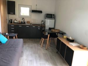una cocina con armarios negros y una mesa con sillas en Charmant gîte en Périgord vert, en Douchapt 14 fotos más