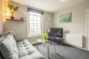 a living room with a couch and a table and a tv at Cambridge 3 bedroom flat with private parking in Cambridge