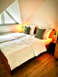 a bedroom with a large white bed with two pillows at Rainbow House Rooms in Maribor