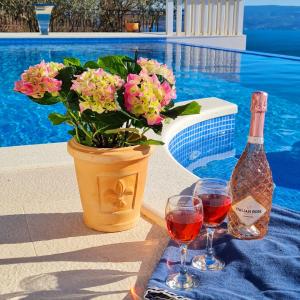 a bottle and two glasses of wine next to a vase with flowers at Sea view Luxury Hotel Villa Conte with private swiming pool and romantic SPA in Podstrana