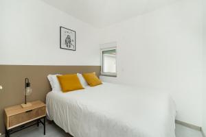 1 dormitorio con cama blanca y almohadas amarillas en Estrela Do Mar Apartment by Olala Homes en Cascais
