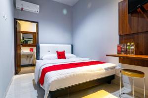 um quarto com uma cama com uma almofada vermelha em RedDoorz near Kebon Jeruk Jakarta em Jakarta