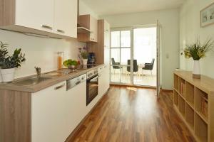 een keuken met witte kasten en een houten vloer bij Uns Huesung in Ahlbeck