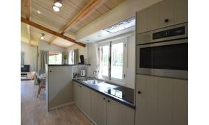 a kitchen with a sink and a stove top oven at Bungalow aan de Visbeekvallei in Vlimmeren