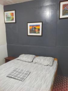 uma cama num quarto com duas fotografias na parede em Nomad Homestay em Moalboal
