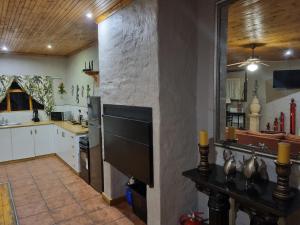 a kitchen with white cabinets and a stone wall at Baroe House in Sutherland