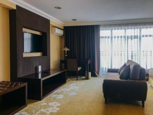 a hotel room with a couch and a television at Shiny River Hotel in Ustʼ-Kamenogorsk