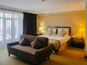 ウスチ・カメノゴルスクにあるShiny River Hotelのベッドとソファ付きのホテルルーム