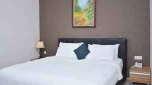 una camera da letto con un letto bianco con un quadro sul muro di Gaia Asri Hotel a Pamanukan-hilir