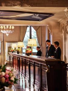 three men standing at a bar in a hotel lobby at Le Meurice – Dorchester Collection in Paris