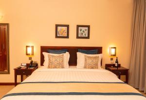 um quarto com uma cama grande com 2 mesas e 2 candeeiros em White Sands Hotel em Dar es Salaam