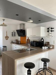 a kitchen with a sink and two bar stools at Appartement Les Corsaires in Granville