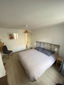 a bedroom with a large white bed and a chair at Appartement Les Corsaires in Granville