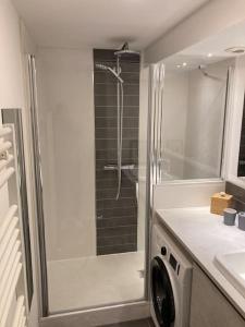a bathroom with a shower and a washing machine at Appartement Les Corsaires in Granville