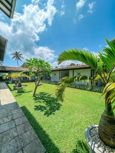 a garden with palm trees and a building at Ubuntu Beach Villas by Reveal in Mirissa