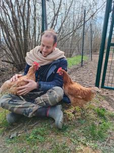 a man is holding two chickens in the grass at B&B Naturin - Cascina Colombaro in Lauriano