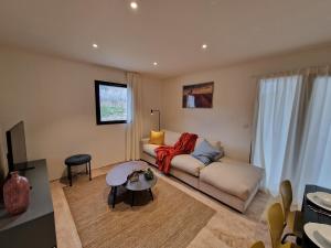 uma sala de estar com um sofá e uma mesa em Les Papillons du Ventoux - L'Aurore de Provence - twee slaapkamerappartement met terras en tuin em Malaucène