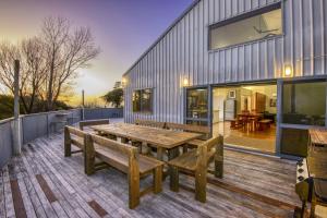 a large deck with a wooden table and benches at THE BARN in Mahia