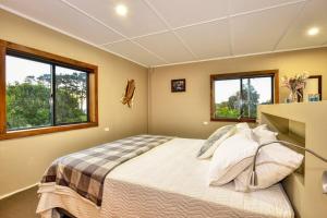 ein Schlafzimmer mit einem Bett und zwei Fenstern in der Unterkunft THE BARN in Mahia