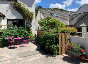 a garden with a table and chairs and plants at Brook beach retreat, Porthtowan, Cornwall in Porthtowan